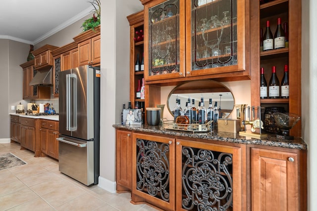 kitchen featuring light tile patterned floors, extractor fan, stainless steel appliances, dark stone countertops, and crown molding