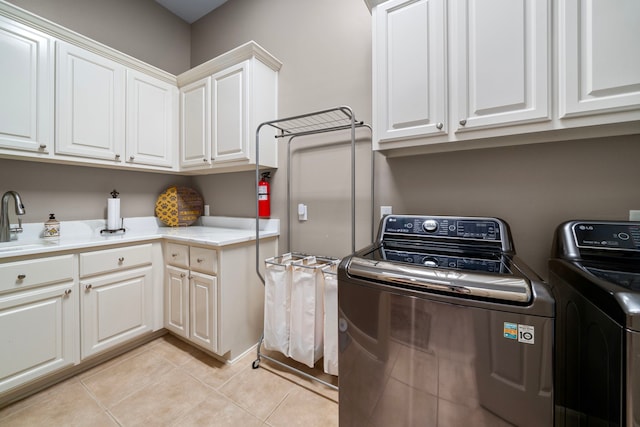 laundry area featuring cabinets, light tile patterned floors, washer and dryer, and sink