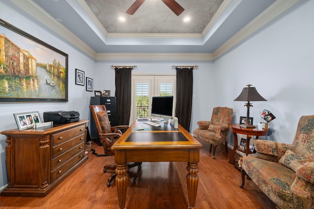 office area featuring crown molding, light hardwood / wood-style floors, a tray ceiling, and ceiling fan