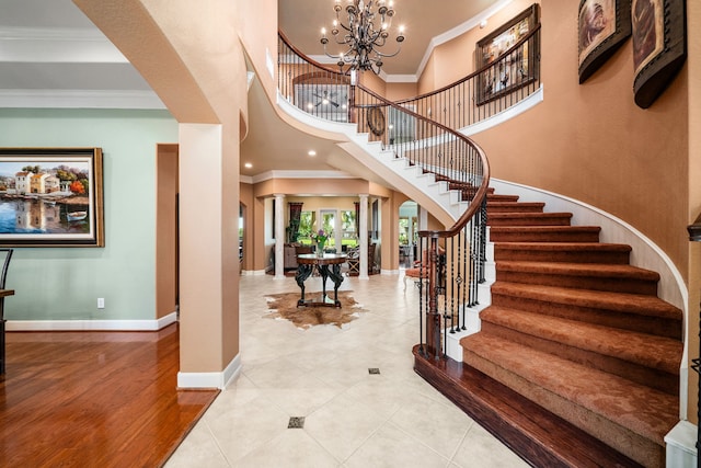 tiled foyer entrance with crown molding, decorative columns, and a chandelier