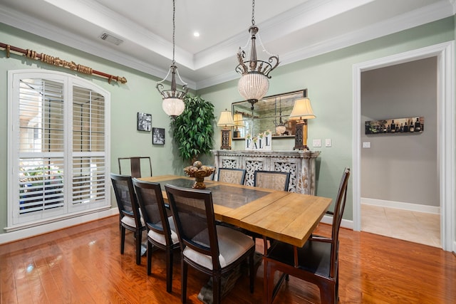 dining room with a chandelier, a tray ceiling, hardwood / wood-style floors, and crown molding