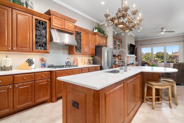 kitchen featuring light tile patterned flooring, sink, an island with sink, stainless steel appliances, and crown molding