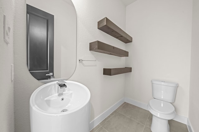 bathroom with toilet, tile patterned floors, and sink