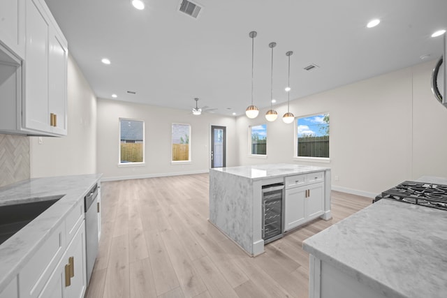 kitchen featuring wine cooler, white cabinetry, light stone countertops, and a kitchen island