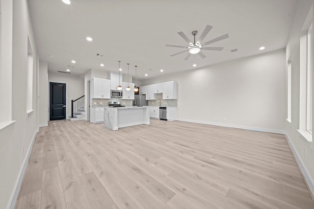 unfurnished living room featuring sink, light wood-type flooring, and ceiling fan