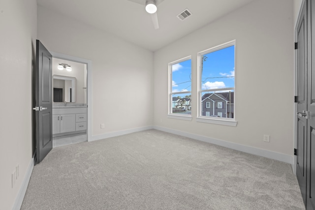 unfurnished bedroom featuring ensuite bath, sink, light colored carpet, and ceiling fan