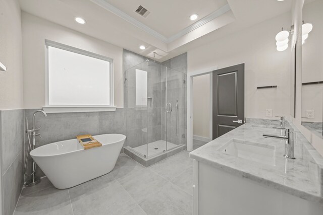 bathroom with vanity, ornamental molding, shower with separate bathtub, and tile walls