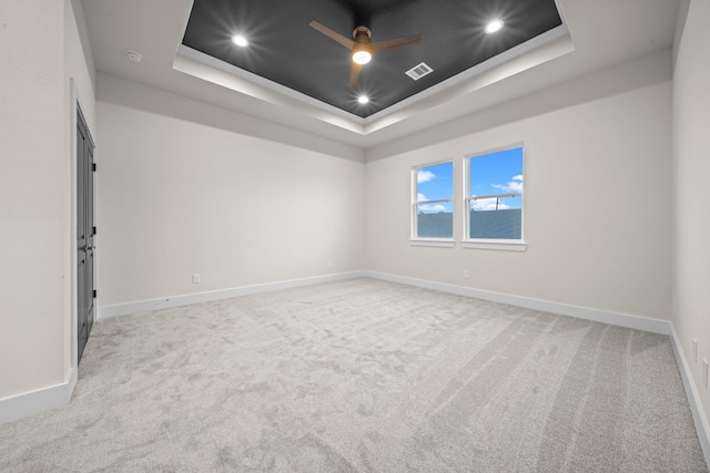 unfurnished room featuring ceiling fan, a tray ceiling, and light colored carpet