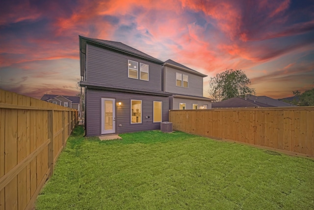 back house at dusk with a lawn