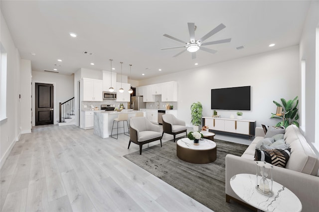 living room featuring sink, light hardwood / wood-style floors, and ceiling fan