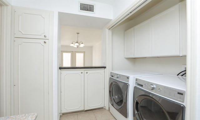 laundry room with light tile patterned flooring, washing machine and dryer, cabinets, and a chandelier