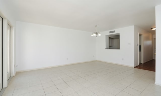 empty room featuring a notable chandelier and light tile patterned floors