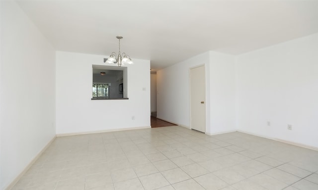 tiled empty room with an inviting chandelier