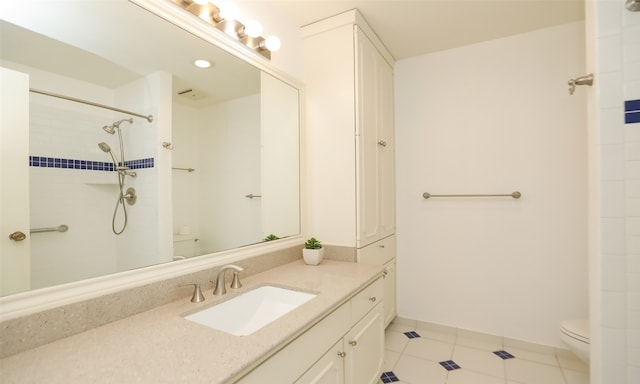 bathroom featuring tile patterned flooring, vanity, tiled shower, and toilet