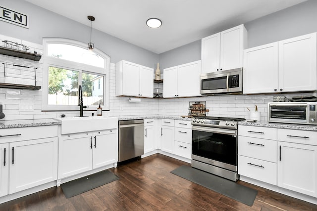 kitchen with sink, white cabinets, hanging light fixtures, appliances with stainless steel finishes, and dark hardwood / wood-style flooring