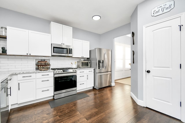 kitchen with appliances with stainless steel finishes, decorative backsplash, white cabinetry, light stone countertops, and dark hardwood / wood-style flooring