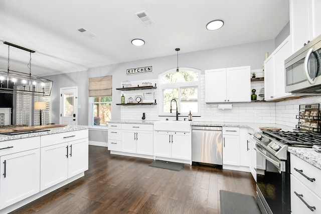 kitchen with dark wood-type flooring, sink, white cabinetry, hanging light fixtures, and stainless steel appliances