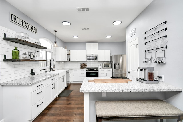 kitchen featuring white cabinets, hanging light fixtures, sink, appliances with stainless steel finishes, and a breakfast bar area