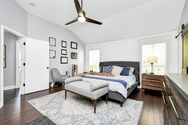 bedroom featuring lofted ceiling, ceiling fan, a barn door, and dark hardwood / wood-style flooring