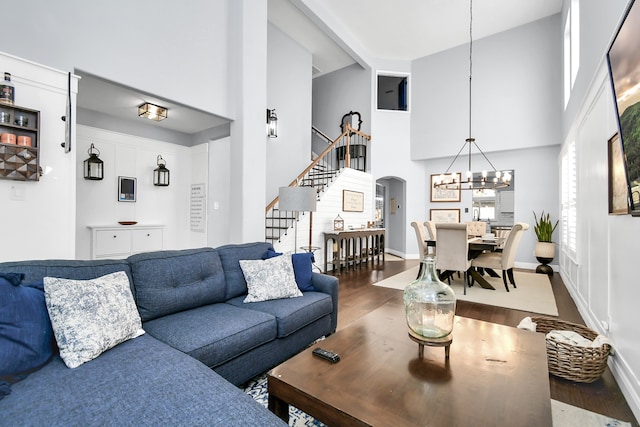 living room with an inviting chandelier, hardwood / wood-style floors, and high vaulted ceiling