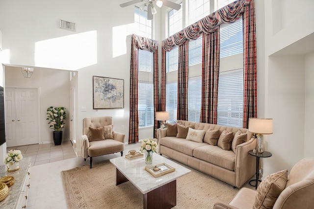 living room featuring ceiling fan, a towering ceiling, and light tile patterned floors