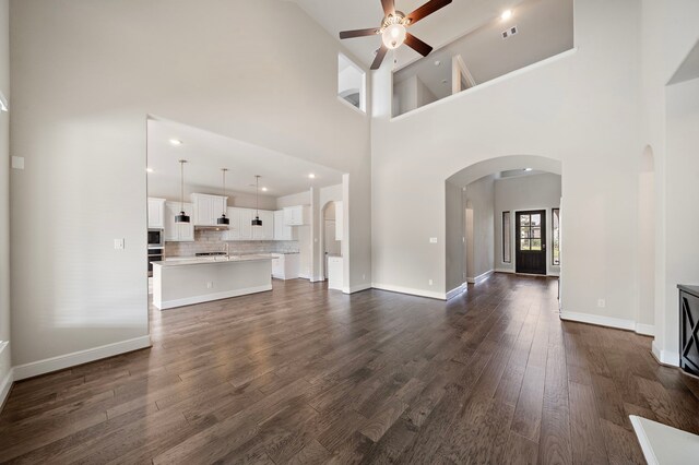 unfurnished living room featuring high vaulted ceiling, ceiling fan, and dark hardwood / wood-style flooring