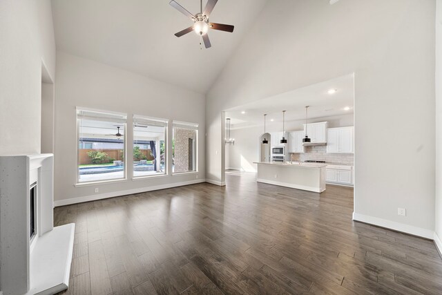 unfurnished living room featuring high vaulted ceiling, ceiling fan, and dark hardwood / wood-style floors