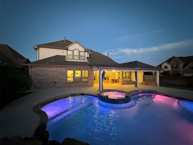 pool at dusk featuring an in ground hot tub and a patio area