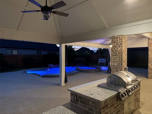 patio terrace at dusk with a gazebo, area for grilling, ceiling fan, and a grill