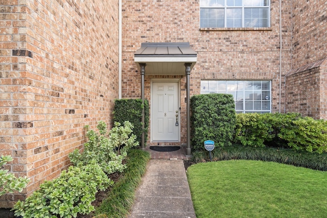 view of exterior entry featuring a lawn