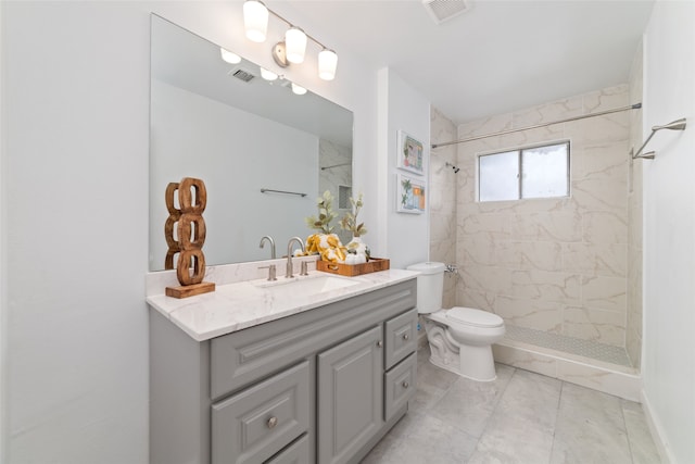 bathroom with vanity, tile patterned flooring, toilet, and tiled shower