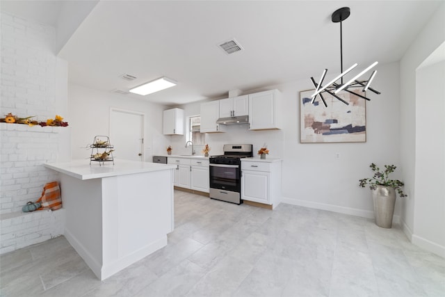 kitchen with stainless steel gas range, white cabinets, kitchen peninsula, hanging light fixtures, and brick wall