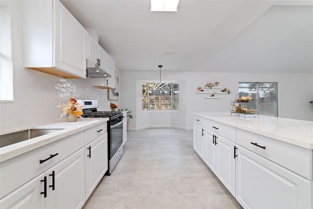 kitchen with tasteful backsplash, white cabinets, gas range, light tile patterned floors, and decorative light fixtures