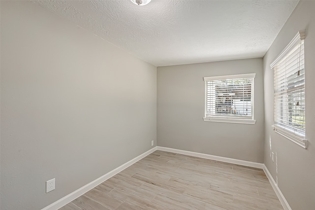 spare room with a textured ceiling and light hardwood / wood-style flooring