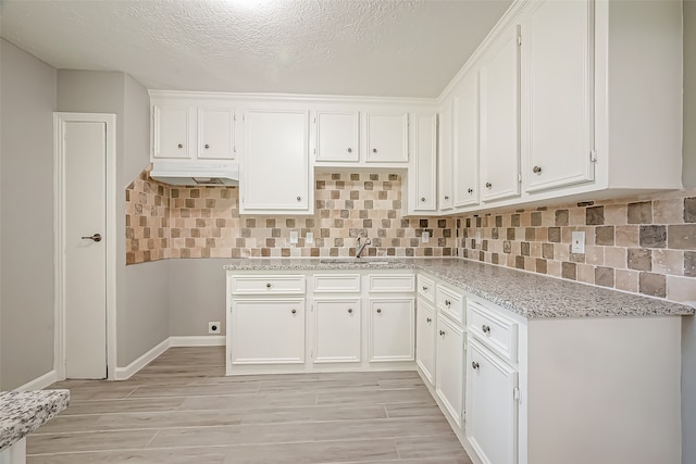 kitchen with white cabinets, a textured ceiling, backsplash, and sink