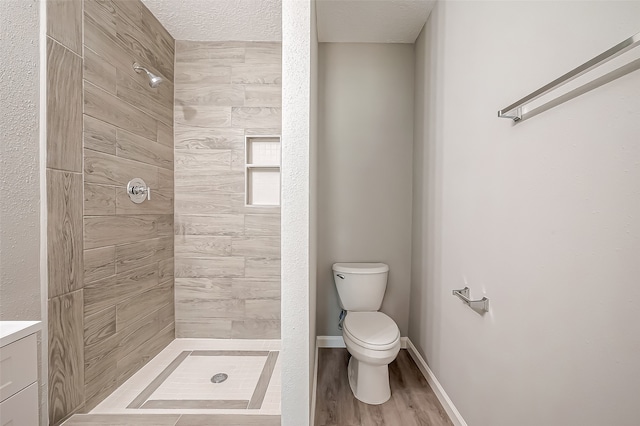 bathroom featuring tiled shower, vanity, a textured ceiling, toilet, and hardwood / wood-style floors