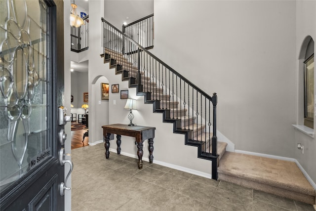 entryway featuring a towering ceiling and tile patterned floors