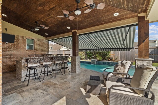 view of patio featuring ceiling fan, a fenced in pool, and an outdoor bar