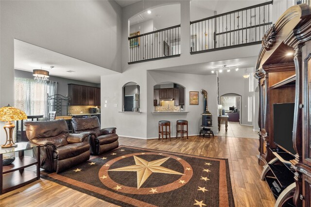 living room featuring a notable chandelier, light wood-type flooring, and a towering ceiling