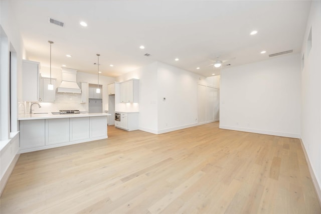 unfurnished living room with ceiling fan, light wood-type flooring, and sink