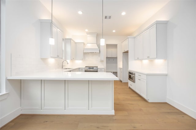 kitchen featuring premium range hood, pendant lighting, kitchen peninsula, decorative backsplash, and white cabinets