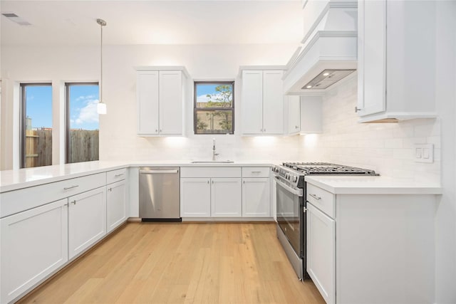 kitchen with white cabinets, pendant lighting, appliances with stainless steel finishes, and custom exhaust hood