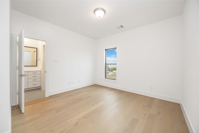 unfurnished bedroom with connected bathroom and light hardwood / wood-style floors