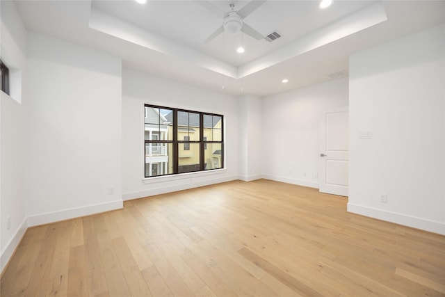 spare room featuring ceiling fan, light hardwood / wood-style floors, and a raised ceiling