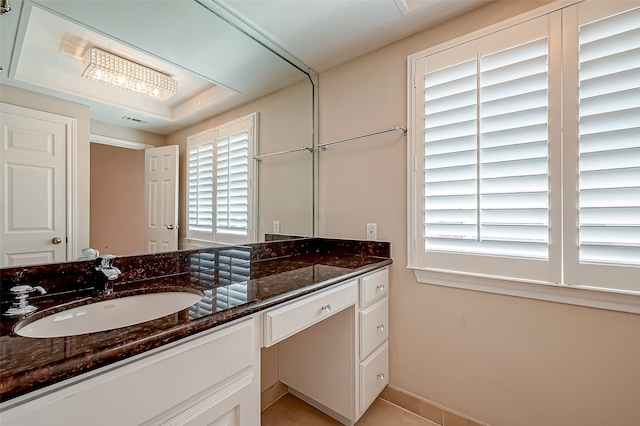 bathroom featuring vanity, a healthy amount of sunlight, and a raised ceiling