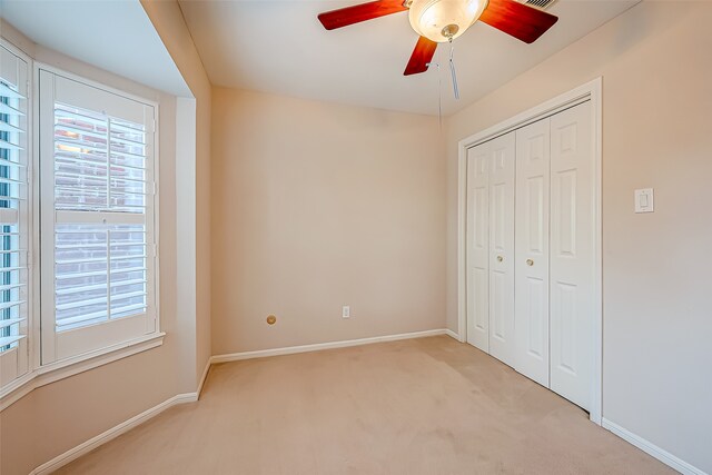 unfurnished bedroom with light carpet, a closet, and ceiling fan