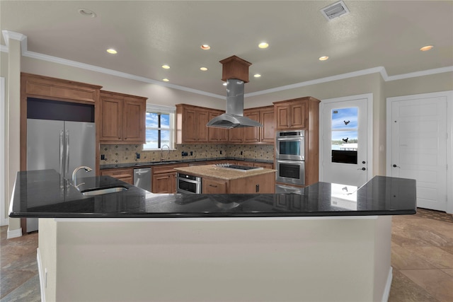 kitchen with sink, island exhaust hood, backsplash, appliances with stainless steel finishes, and a spacious island