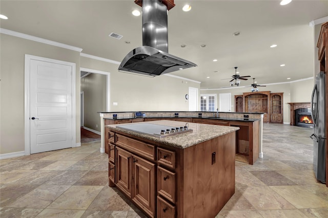 kitchen with dark stone counters, a center island, island range hood, appliances with stainless steel finishes, and crown molding