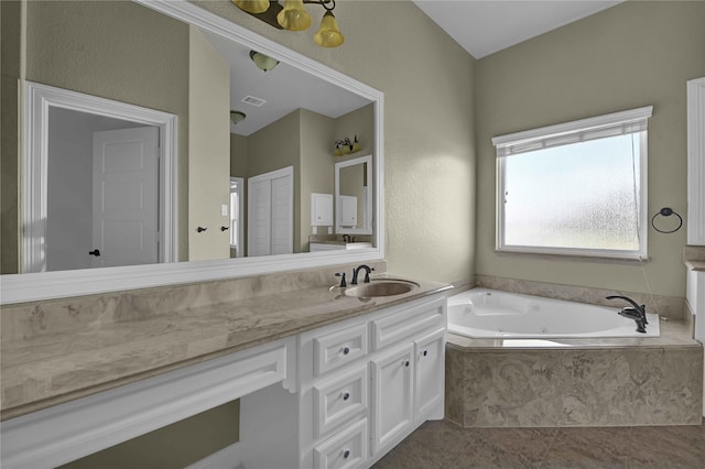 bathroom with tiled tub, vanity, and tile patterned flooring