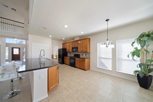 kitchen featuring decorative backsplash, an inviting chandelier, black appliances, decorative light fixtures, and sink